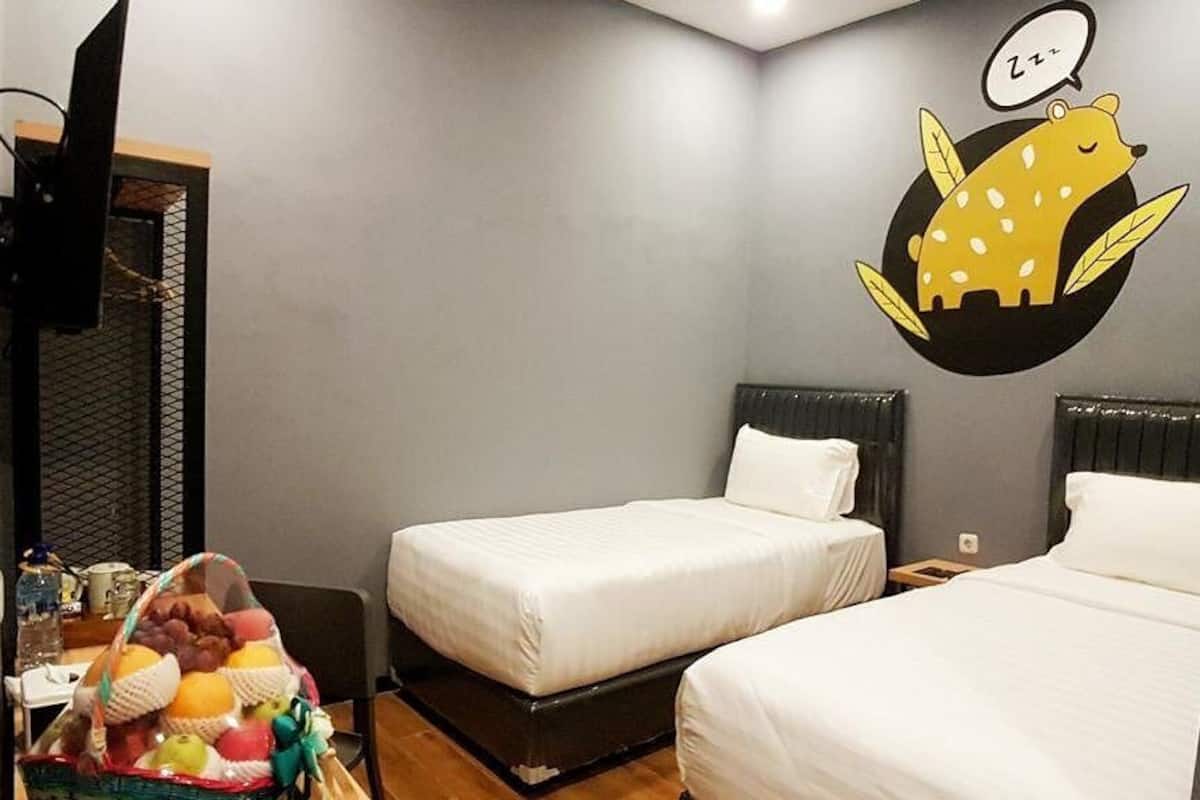 Quarto de hotel com duas camas, uma televisão e uma decoração de parede representando um animal dormindo.