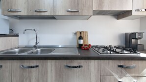 Una cucina moderna con mobili in legno, un lavello in acciaio inossidabile, una bottiglia di vino e un piano cottura a gas.