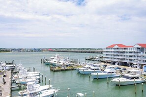 Ein Yachthafen mit mehreren anglegerten Booten, einer anlegenden Pier und einem großen Gebäude mit rotem Dach.