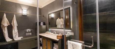 A modern bathroom with a glass shower enclosure, a vanity with a mirror, and a towel rack.