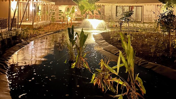 Vue nocturne d'un complexe hôtelier avec des tentes et une fontaine centrale.