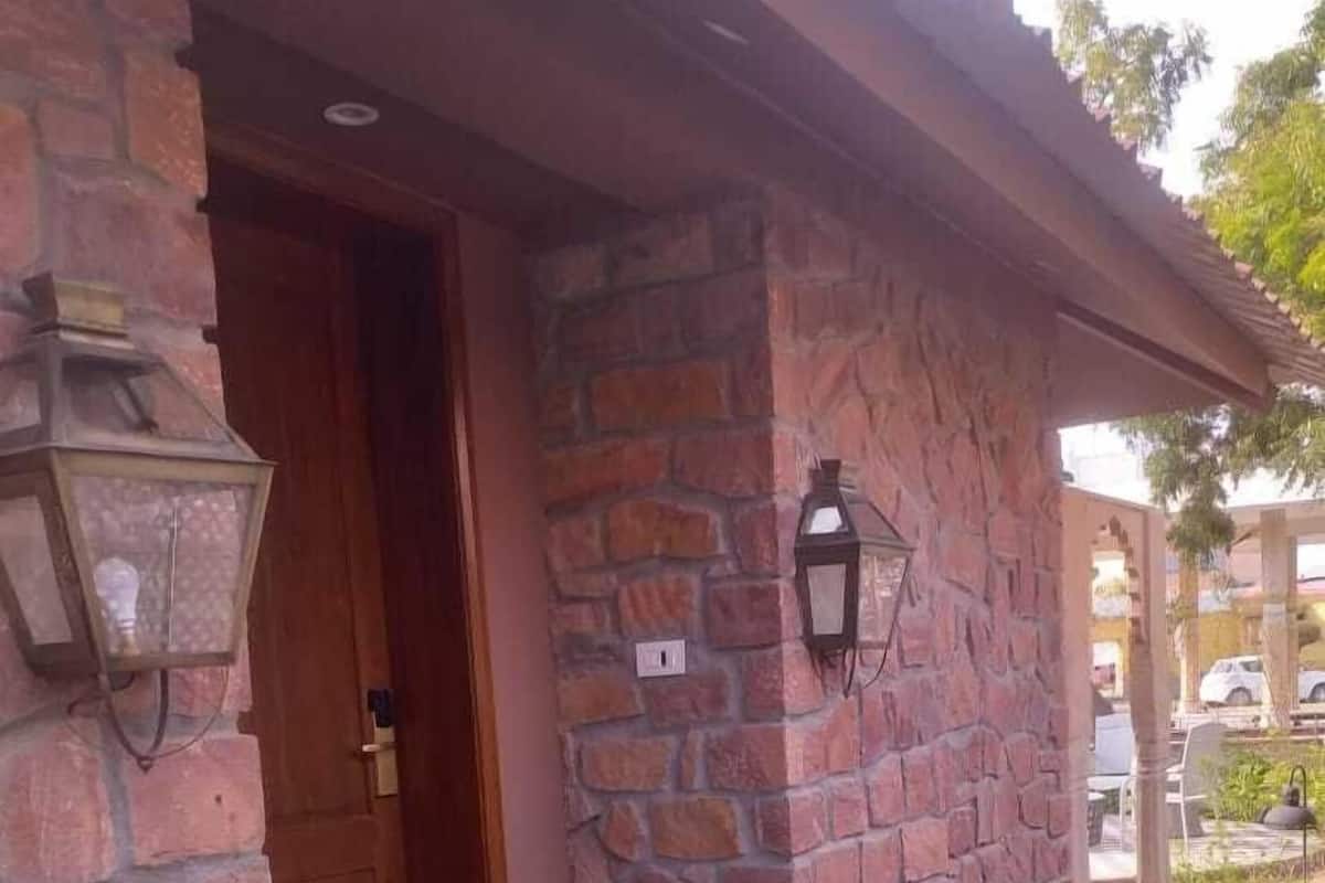Een gebouw van steen met een houten deur, een klein terras en twee lantaarns aan de muur.