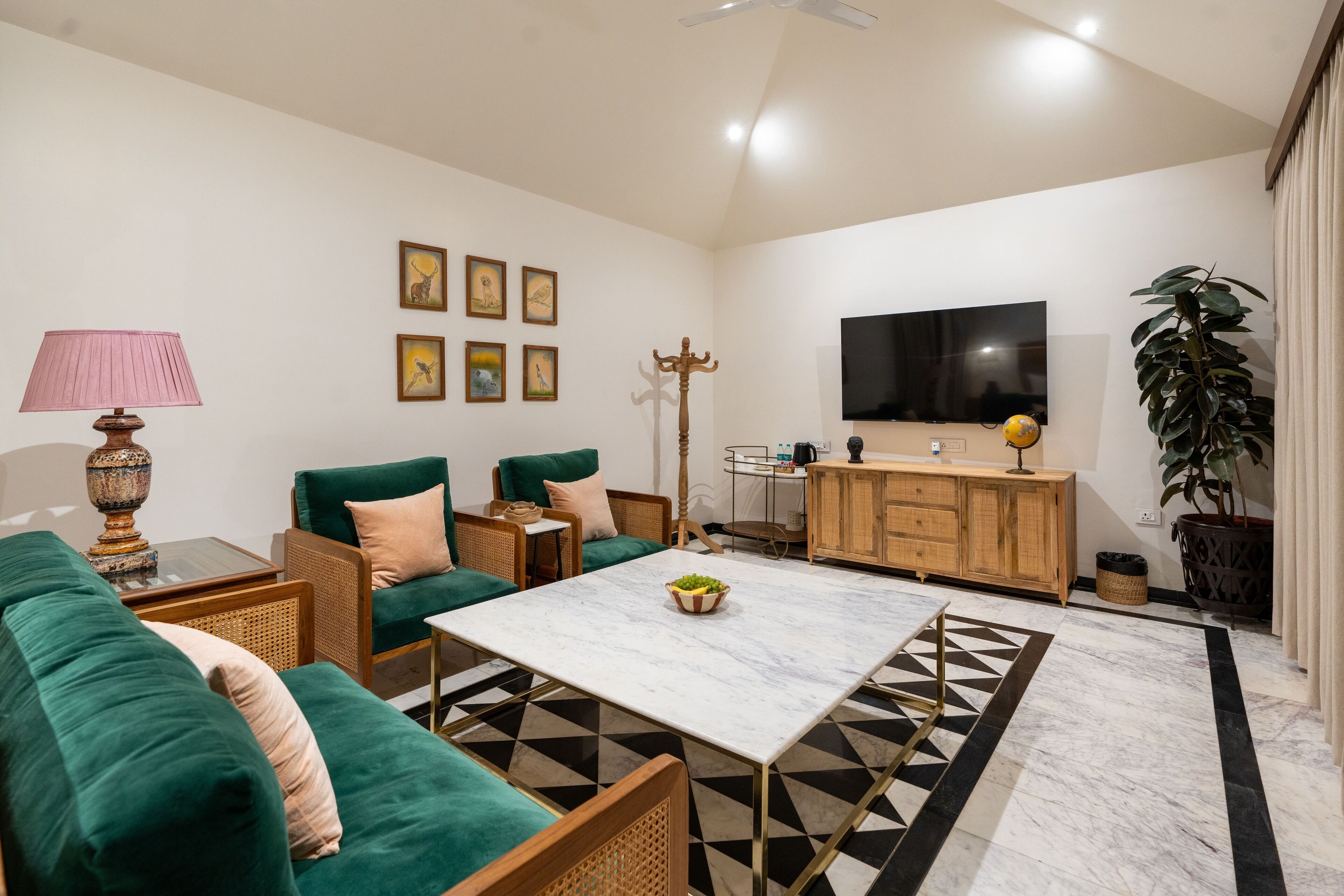 Ein Wohnzimmer mit einem grünen Sofa, einem Couchtisch, einem Fernseher und einer Pflanze.