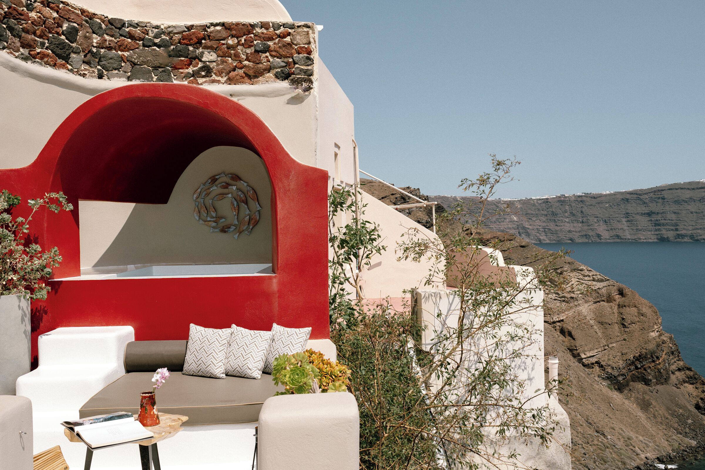 A coastal building with a red archway, white walls, and a view of the sea.