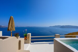 A seaside terrace with a view of the ocean, a sun lounger, potted plants, and a small pool.