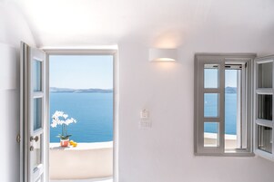 A room with a view of the sea, a potted plant, and a light switch on the wall.
