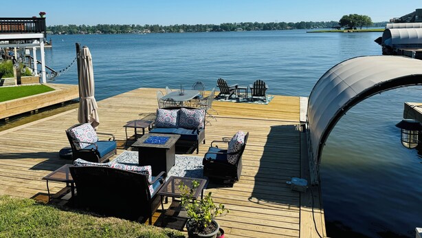 A wooden deck with outdoor furniture, a covered area, and a view of a lake. - Hidden Gem Waterfront home in gated Country Club community on Lake Conroe.   (Montgomery)
