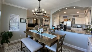 A modern kitchen with a central island, built-in appliances, and a dining area with a chandelier. - Hidden Gem Waterfront home in gated Country Club community on Lake Conroe.   (Montgomery)