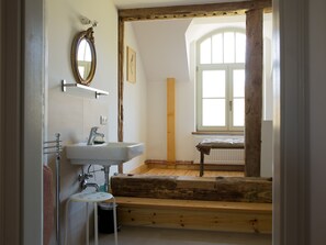 Ein Badezimmer mit einer Holzbank, einem Waschbecken und einem großen Spiegel.