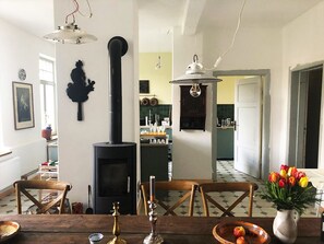 Ein Essbereich mit Holztisch, Stühlen, einer Tulpenvase und einem schwarzen Herd.