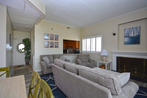 A living room with a sofa set, a fireplace, and a dining area with chairs.
