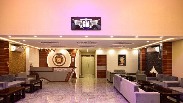 Un vestíbulo de hotel con mostrador de recepción, sofás y una zona de recepción con un reloj y un cartel.