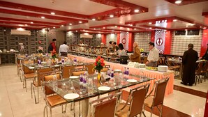 Un comedor tipo bufé con varias mesas y sillas, que presenta un diseño moderno con tapas de vidrio y estructura metálica.