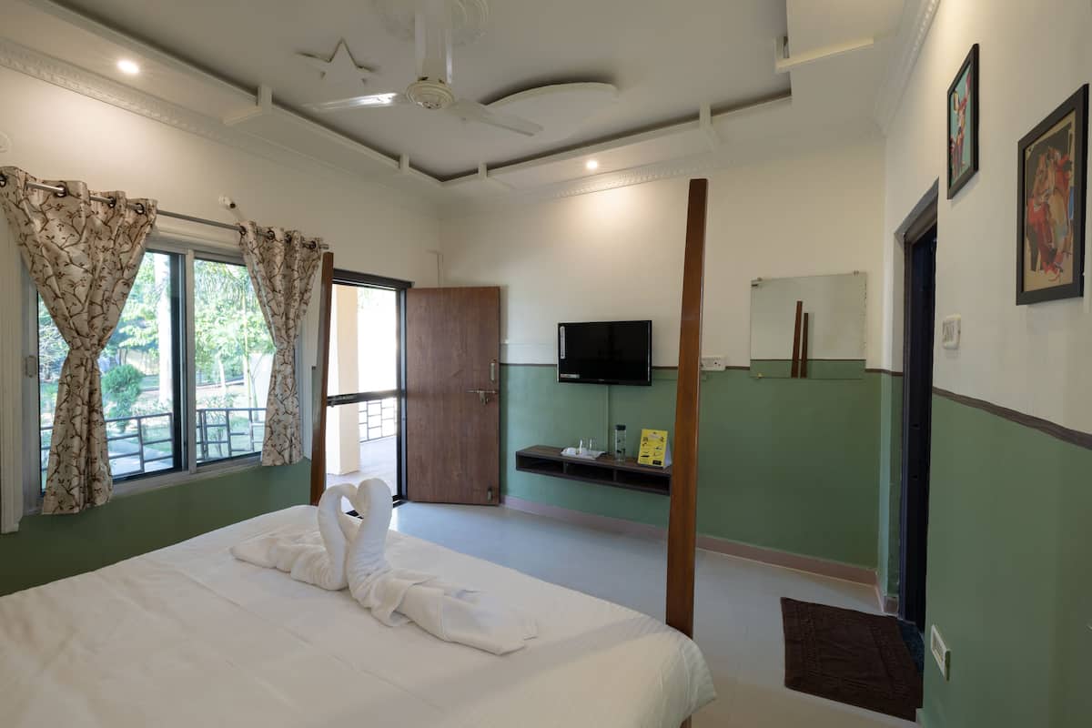 A hotel room with a large bed, a ceiling fan, a TV, and a green accent wall.