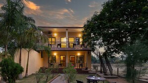 A two-story building with a balcony, outdoor seating, and a staircase leading to an upper level. - Avadale Tadoba - Stag Groups Not Allowed (Bhadravathi)