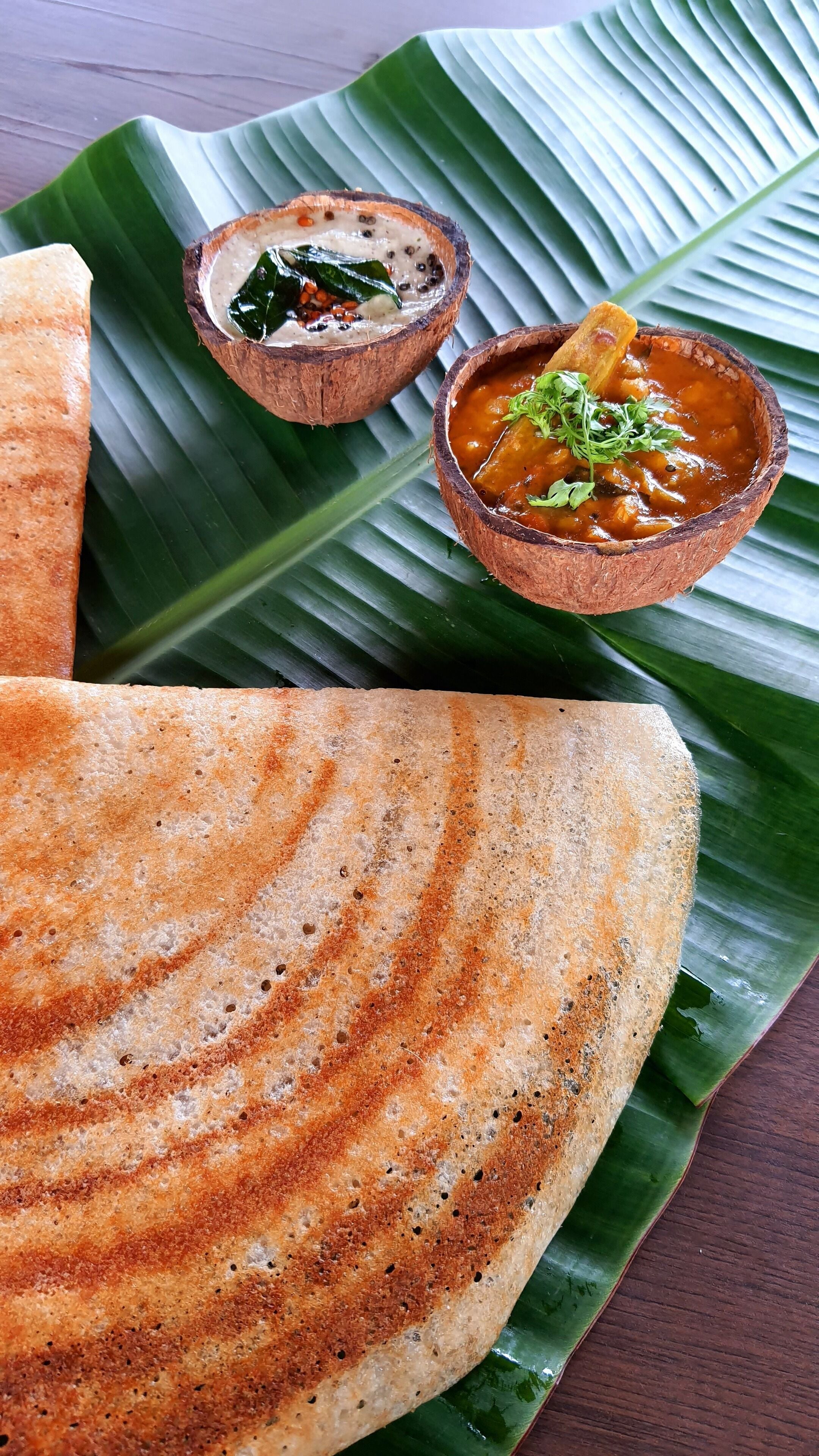 Dosa acompañada de dos guarniciones sobre una hoja de plátano.