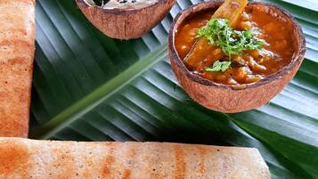 Dosa acompañada de dos guarniciones sobre una hoja de plátano.