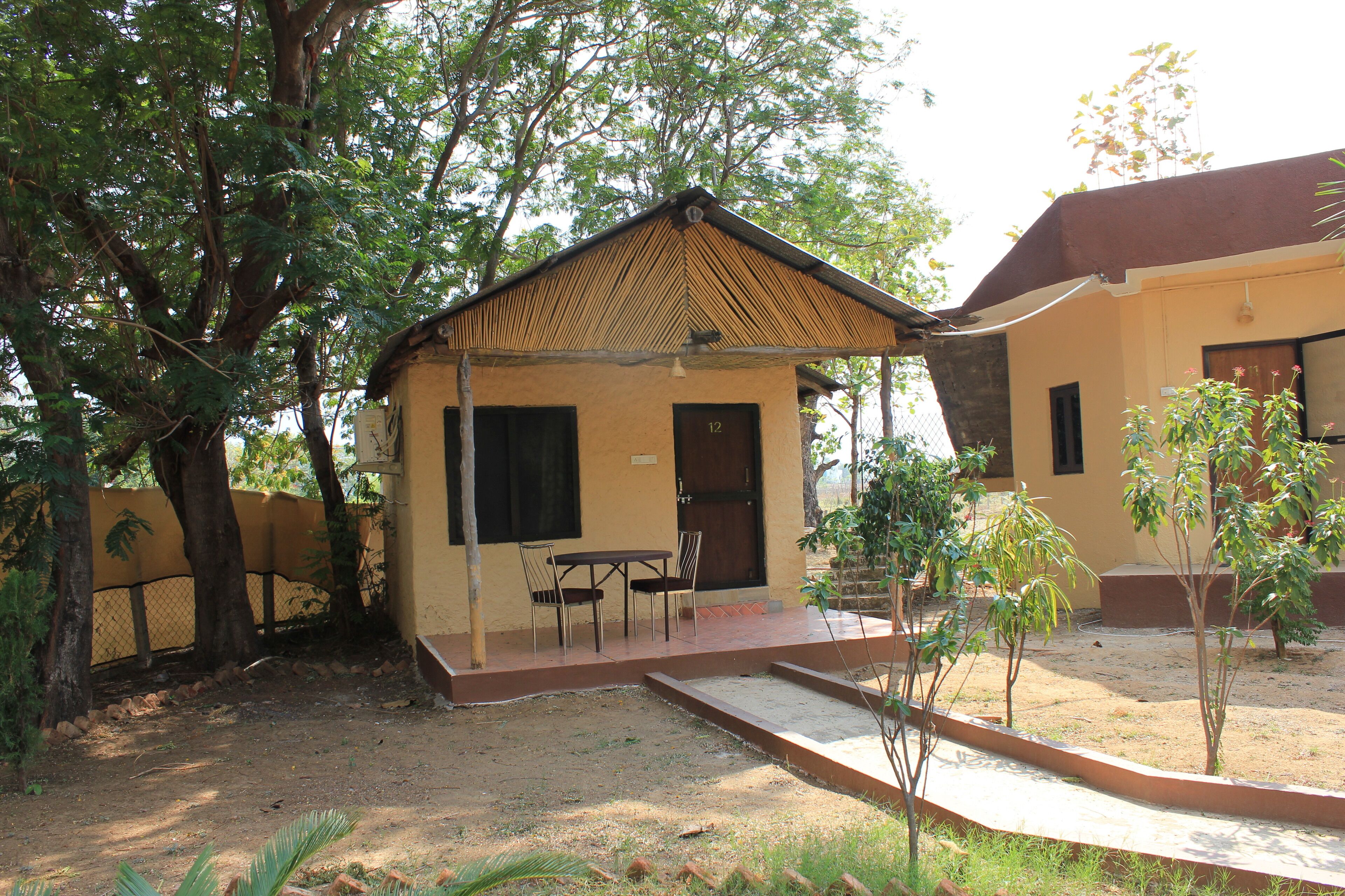 A small building with a covered patio, a table and chairs, and a door marked with the number 12.