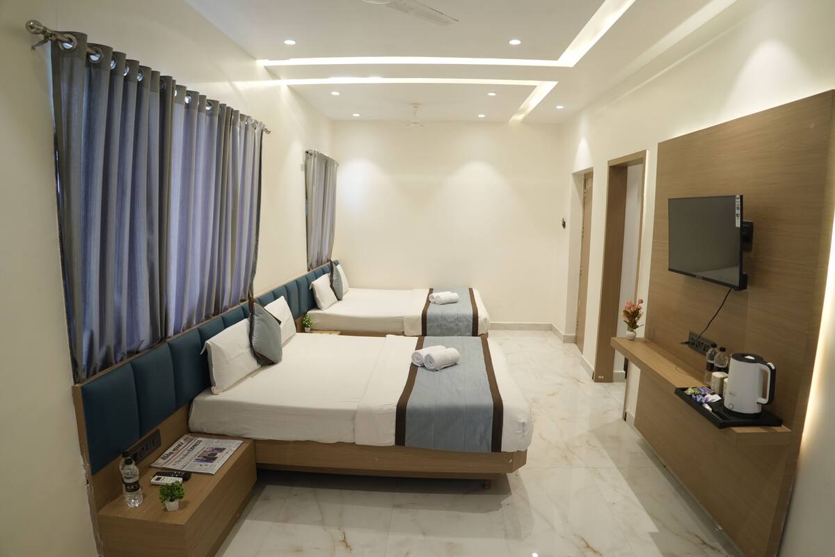 A hotel room with two beds, a TV, a wooden reception desk, and a marble floor.