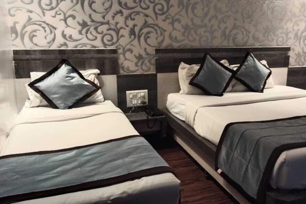A hotel room with two beds, each with a headboard and pillows.