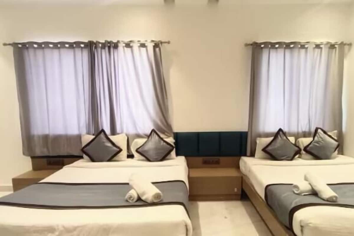 A hotel room with two beds, each with a pillow and a rolled towel.
