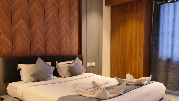 A modern bedroom with a large bed, wooden panel walls, and an air conditioning unit. - Kiara Eshosans Palace  (Rahata)