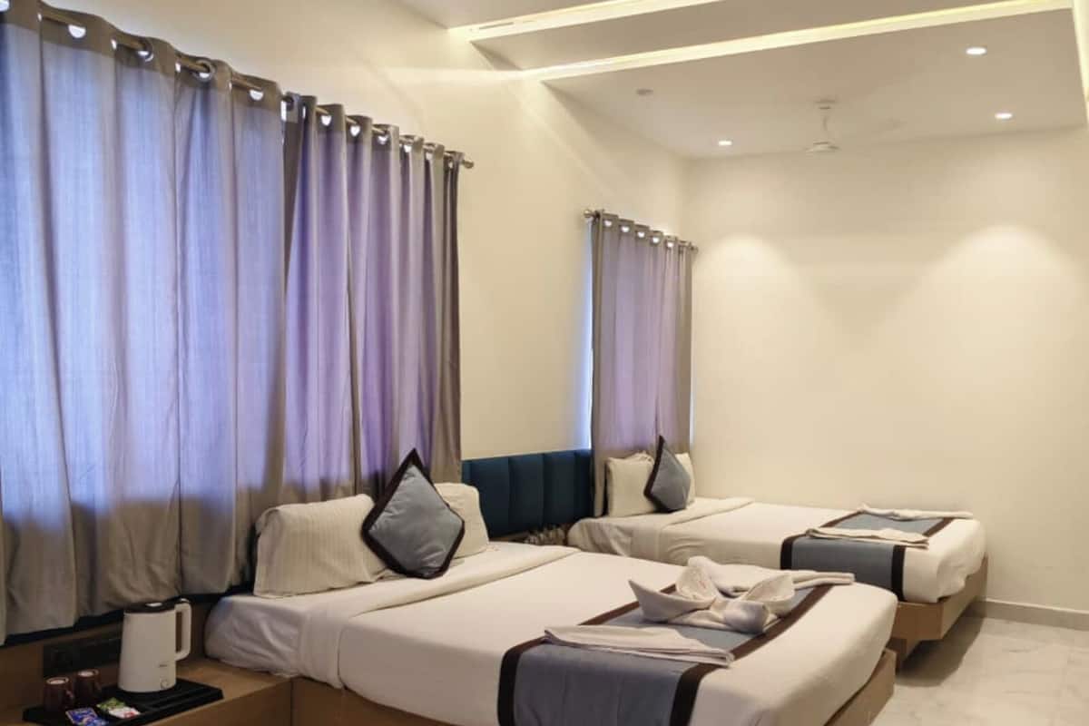 A hotel room with two beds, a ceiling fan, and a nightstand with a coffee maker.