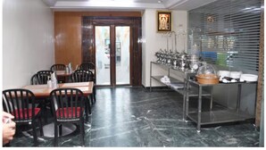 A dining area with a marble floor, wooden door, and a buffet setup with stainless steel appliances. - Kiara Eshosans Palace  (Rahata)