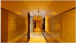 A hotel corridor with a marble floor, wooden walls, and pendant lighting. - Kiara Eshosans Palace  (Rahata)