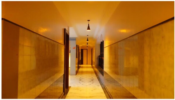 A hotel corridor with a marble floor, wooden walls, and pendant lighting. - Kiara Eshosans Palace  (Rahata)