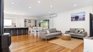 A modern living room with two grey sofas, a coffee table, and a TV. - Swell Times Holiday Home - Busselton (West Busselton)