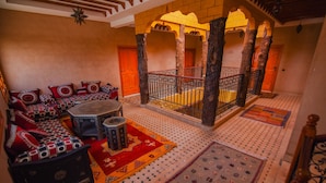 A traditional interior with a patterned sofa set, a round table, and a decorative rug. - Kasbah Roseville  (Ait Sedrate Sahl El Gharbia)