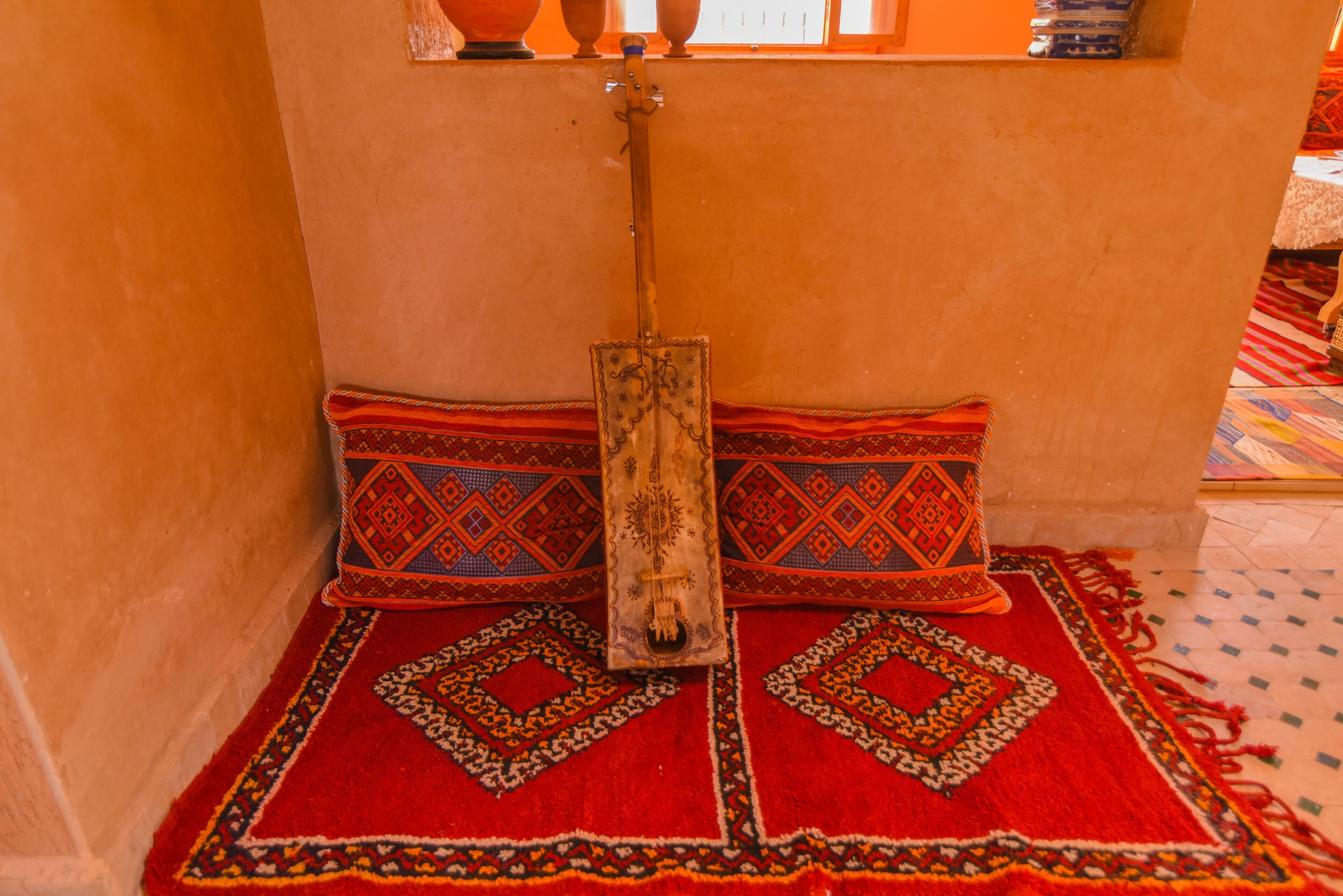 Una habitación con alfombra roja estampada, estructura de cama de madera y ventana con vistas al exterior.