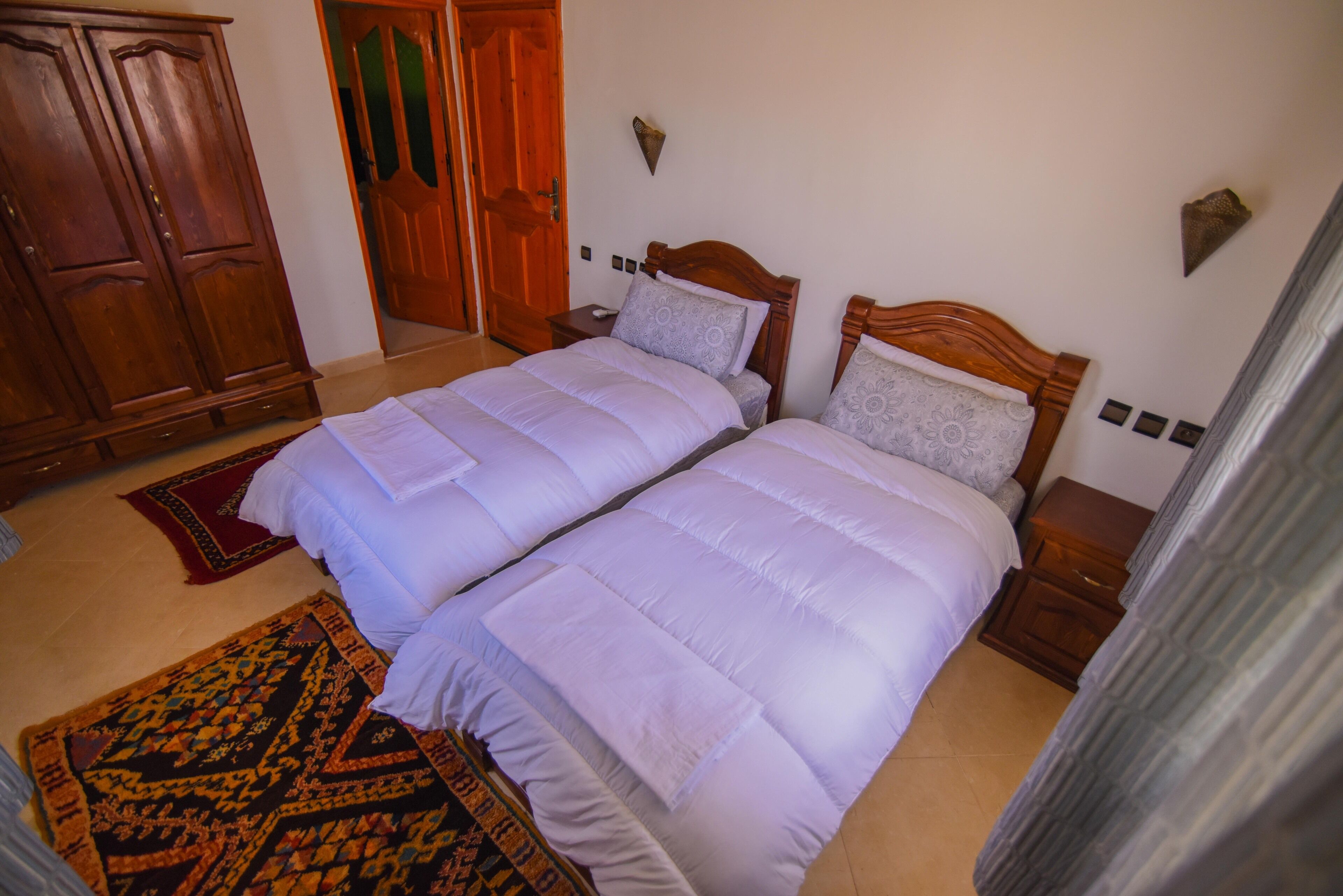 Un lit double avec une tête de lit en bois, une table de chevet et un tapis à motifs.
