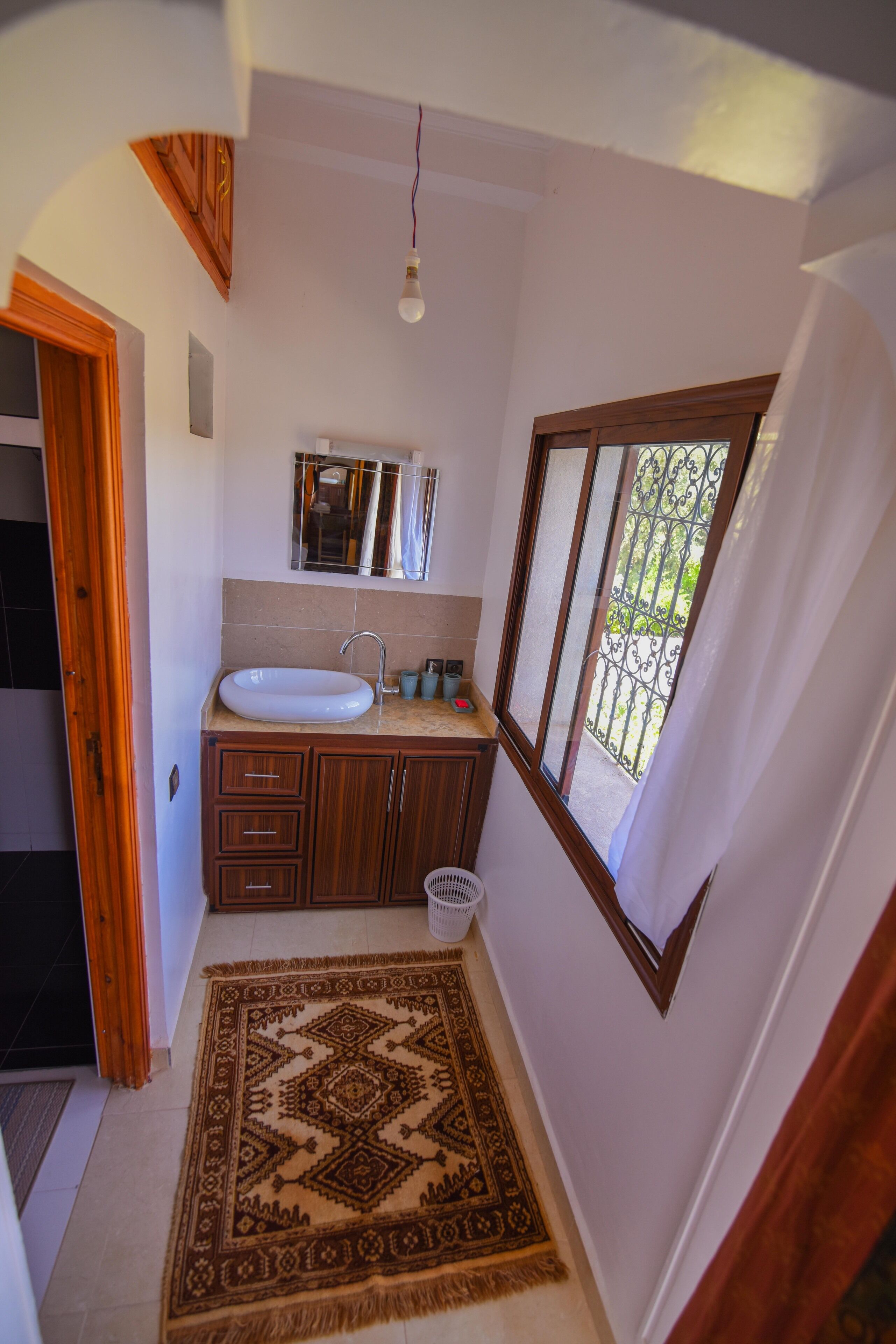 A small bathroom with a sink, mirror, and window.