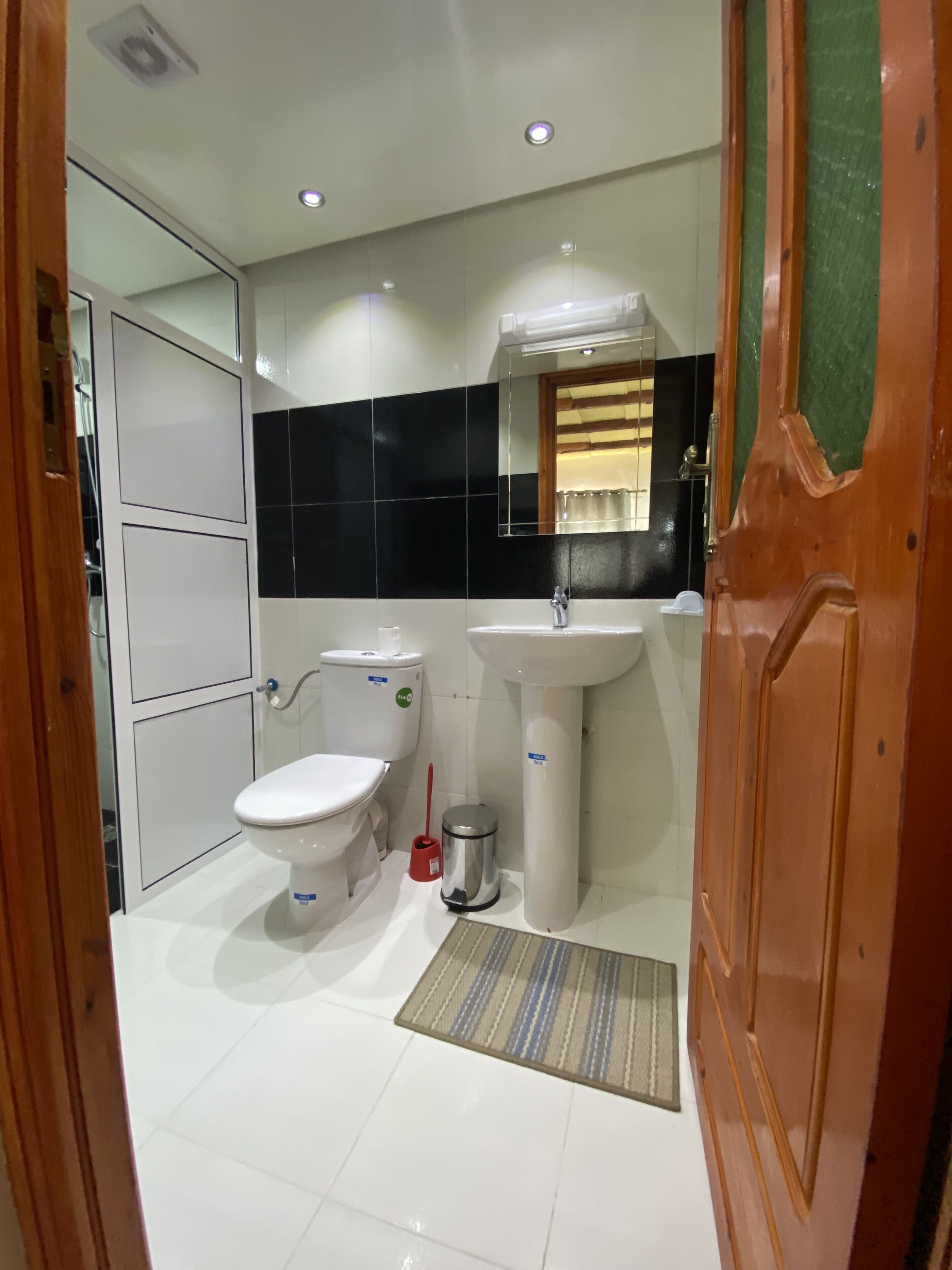 A bathroom with a toilet, sink, and mirror.