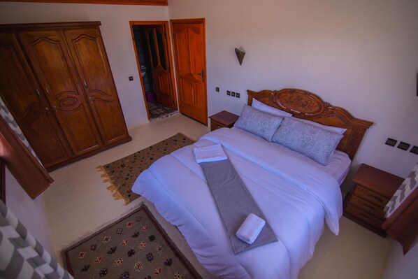 Un dormitorio con una cama grande, un armario de madera y una mesita de noche pequeña.