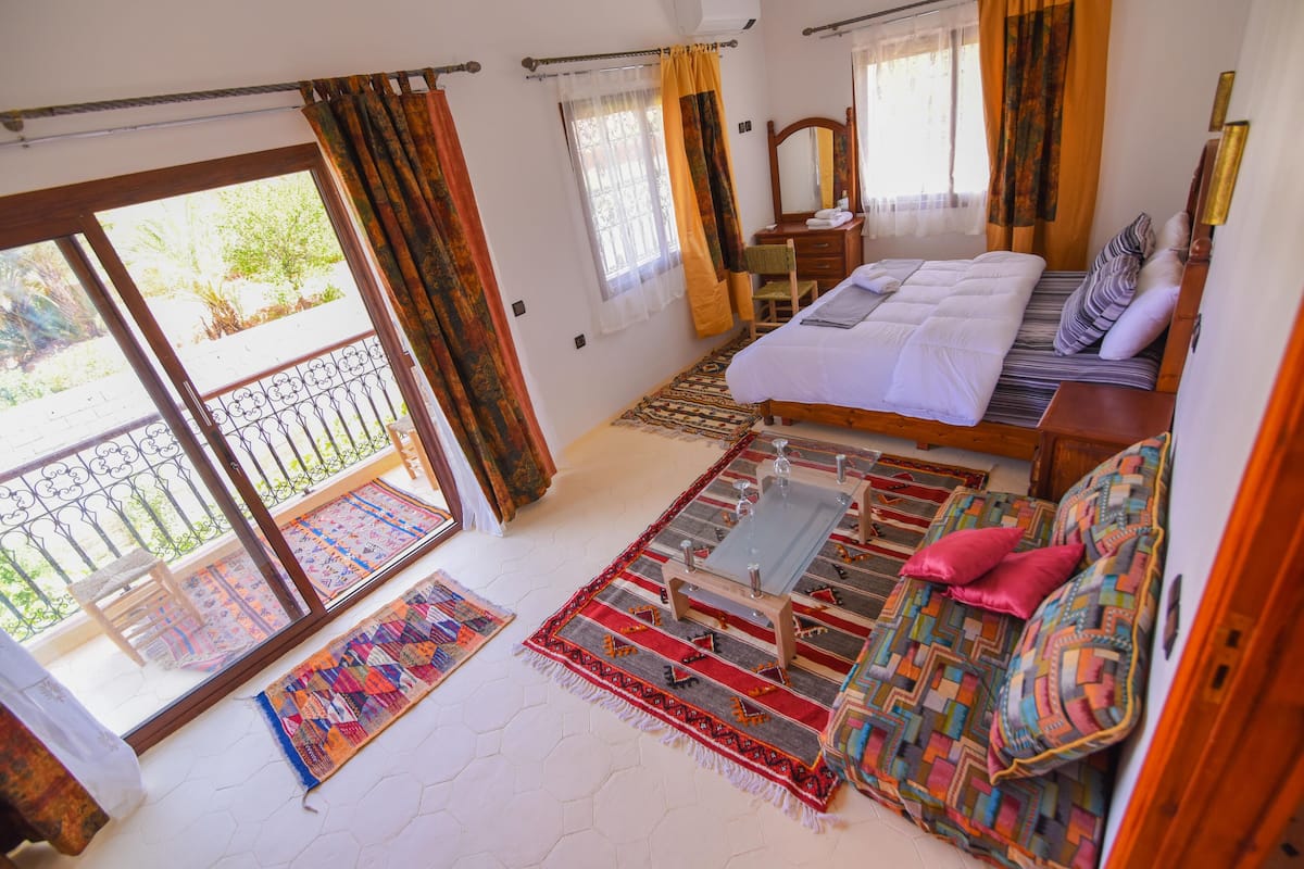 Une chambre avec un lit, un canapé, une petite table et un balcon avec vue.