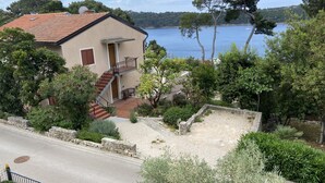 Una casa de dos pisos con techo de tejas rojas, una escalera y vistas a un lago.