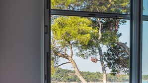 Un dormitorio con cama, ventana y vistas a un árbol y al agua.