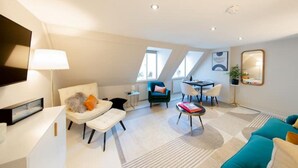 A modern living room with a sofa, chairs, a coffee table, and a dining area. There are skylights and a large mirror on the wall. - Hidden Gem in Covent Garden, contemporary design with private terrace (London)