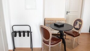 A small dining area with a round table, two chairs, and a black chair with a backrest. - ANA Suites Augsburg City Center (Augsburg)