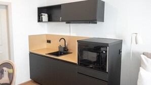 A compact kitchen with a black countertop, a built-in microwave, and a small sink. - ANA Suites Augsburg City Center (Augsburg)