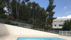 En rektangulär swimmingpool med klart, blått vatten, omgiven av en vit mur och ett staket.