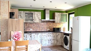 A compact kitchen with a dining area, featuring a coffee machine, a washing machine, and a refrigerator. - Wunderschönes Apartment Ob12-e mit Terrasse in Mainz (Mainz)