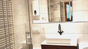 A modern bathroom with a glass shower enclosure, a toilet, a sink with a mirror above, and a vanity with drawers. - Wunderschönes Apartment Ob12-e mit Terrasse in Mainz (Mainz)