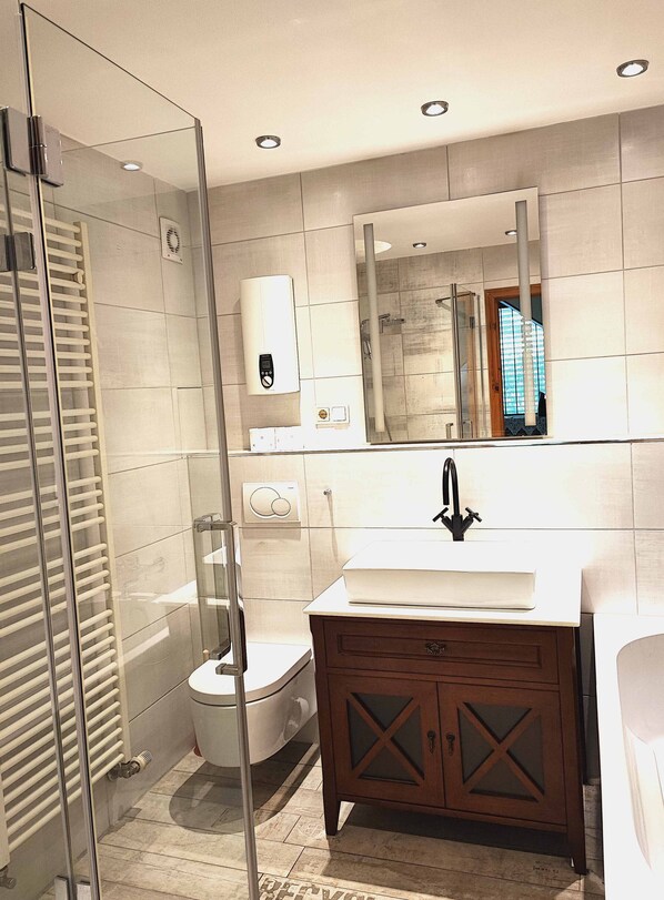 A modern bathroom with a glass shower enclosure, a toilet, a sink with a mirror above, and a vanity with drawers. - Wunderschönes Apartment Ob12-e mit Terrasse in Mainz (Mainz)