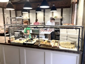 A bakery display case with various baked goods, a counter with a metal railing, and a brick wall in the background. - Pure Luxury Suite Friendly Calm Residence Prague (Hlavní město Praha)