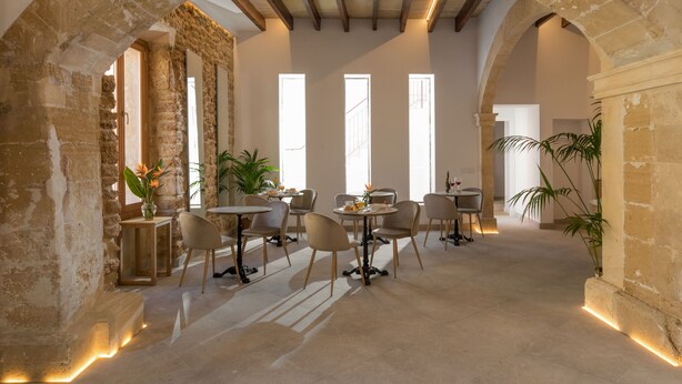 A spacious dining area with stone arches, multiple tables, and chairs. - Petit Palau Alcudia Boutique Hotel (Alcúdia)