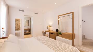 Une chambre d’hôtel moderne, dotée d’un grand lit, d’un bureau, d’un miroir et d’une salle de bain visible à travers une porte ouverte.